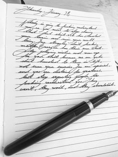 a pen sitting on top of an open notebook next to a paper with writing on it