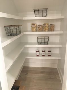 an empty pantry with white shelving and baskets