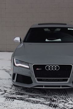 an audi car parked in front of a building on a snow covered parking lot with no one around it