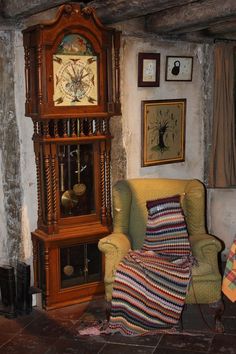 a living room with a grandfather clock on the wall next to a chair and rug