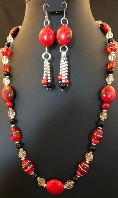 This necklace is set with red stones, red oval glass beads and red rounds.  Interspersed with all this red, there was clear glass, black rounds and silver disks in a symmetrical pattern.  The set's earrings showed a red stone and red, black, silver beads. Black Jewelry Set, Symmetrical Pattern, Red Stones, Black Jewelry, Silver Bead, Bead Jewelry, Red Stone, Black And Silver, Jump Rings