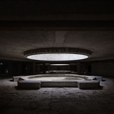 an empty room with benches in the center and lights on above it at night time