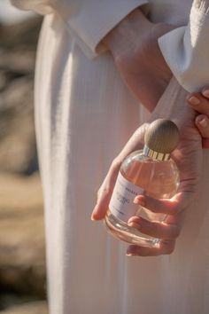 a woman holding a bottle of perfume in her hand