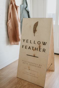 a wooden sign sitting on top of a hard wood floor next to a coat rack