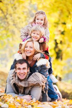 a woman and two children are posing for a photo in the leaves with their parents