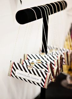 several pieces of chocolate hanging from strings in front of a white wall with black and gold stripes