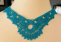 a blue crocheted necklace on a mannequin neckline with holes in the middle