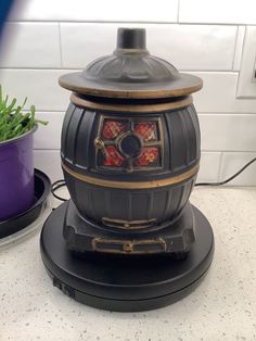 an old fashioned stove sitting on top of a counter next to a potted plant