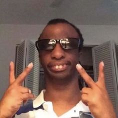 a man wearing sunglasses making the peace sign