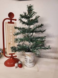 a small christmas tree sitting on top of a table next to an old fashioned sign