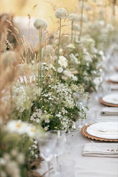 the table is set with white plates and flowers