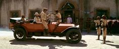 an old car with men standing around it