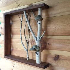 a tree made out of branches hanging from a wooden frame on the wall in front of a wood paneled wall