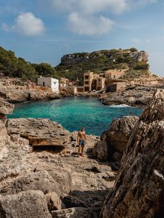 two people standing on rocks near the ocean