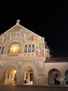 an old church with paintings on the side and stained glass windows in it at night