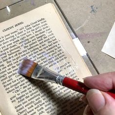 a person holding a brush over an open book