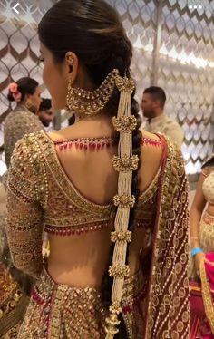 the back of a woman's wedding dress with gold and red jewelry on it