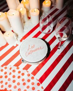 the table is set with wine glasses, candles and paper napkins that read les catounes