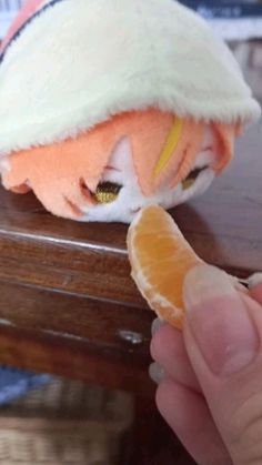 an orange slice is being held up to the side of a doll's head