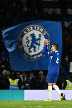 a soccer player in blue uniform standing on the field with his hand up to his face