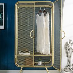 a white dress is hanging on a rack in the corner of a room with blue walls