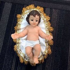 a small baby doll in a gold frame on a black tablecloth with a white blanket around it