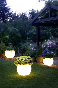 three large planters filled with flowers in the grass