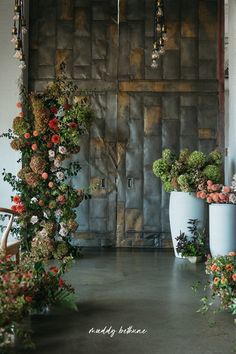 two large vases filled with flowers sitting next to each other in front of a wooden door