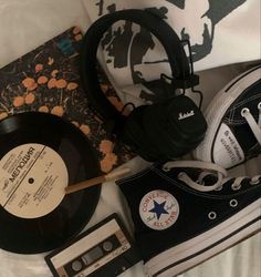 an old pair of black sneakers, headphones, and record player on a bed