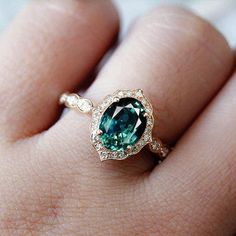 a close up of a person's hand with a green ring on their finger