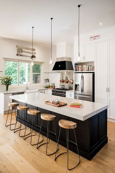 a kitchen island with four stools next to it and an oven in the background