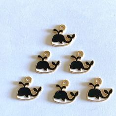 six black and gold whale charms on white background