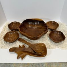 five wooden bowls and spoons on a doily