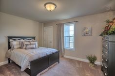 a bedroom with a bed, dresser and window in it's centerpieces