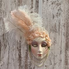 a mannequin's head with feathers and pearls on it against a wooden wall