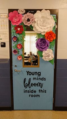 a door decorated with paper flowers and the words, young minds bloom inside this room