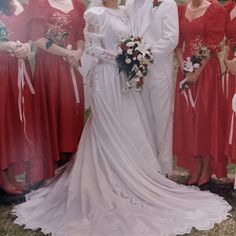 a group of women standing next to each other wearing red dresses and holding bouquets