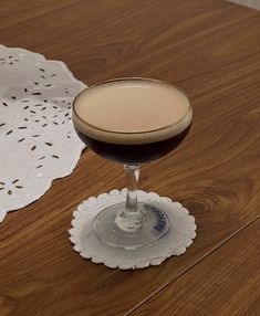 a drink sitting on top of a wooden table next to a doily covered place mat