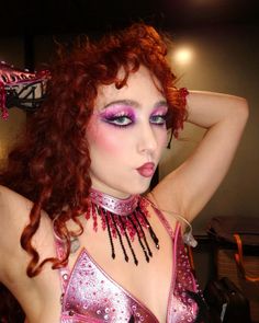 a woman with red hair and makeup is posing for the camera wearing a pink outfit