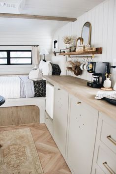 a bedroom with white walls and wood flooring next to a bed in a small room