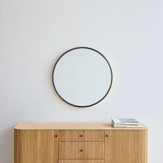 a round mirror on the wall above a dresser