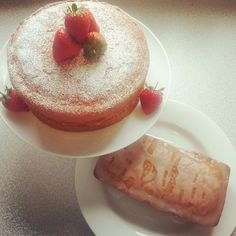 a white plate topped with a cake covered in powdered sugar next to a piece of fruit