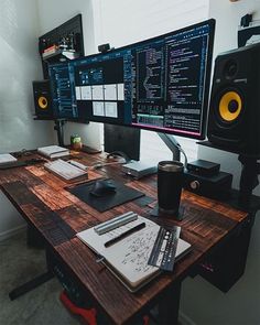 a desk with two computer monitors, keyboard and mouse next to speakers on the wall