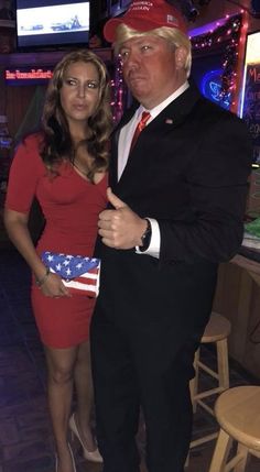 a man in a suit and tie standing next to a woman wearing a red dress