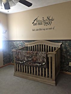 a baby crib in the corner of a room with mossy walls and deer decals on the wall