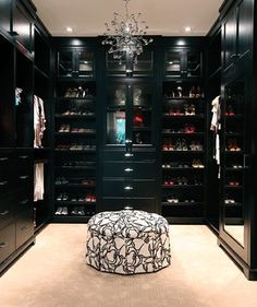 a walk - in closet with black cabinets and chandelier