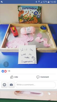 a wooden tray filled with pink paper cut outs on top of a blue table next to a book