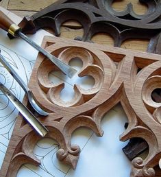 some wood carvings are being worked on with scissors and pencils in front of them