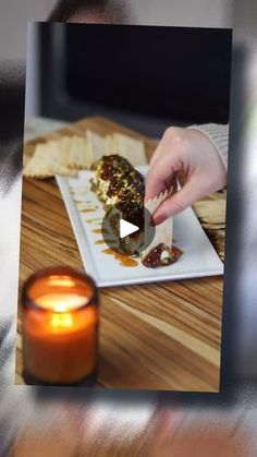 a person is eating food on a plate with a candle in front of them and the screen has an image of someone holding a knife