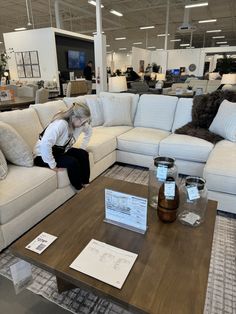 a woman sitting on top of a white couch in a living room next to a coffee table